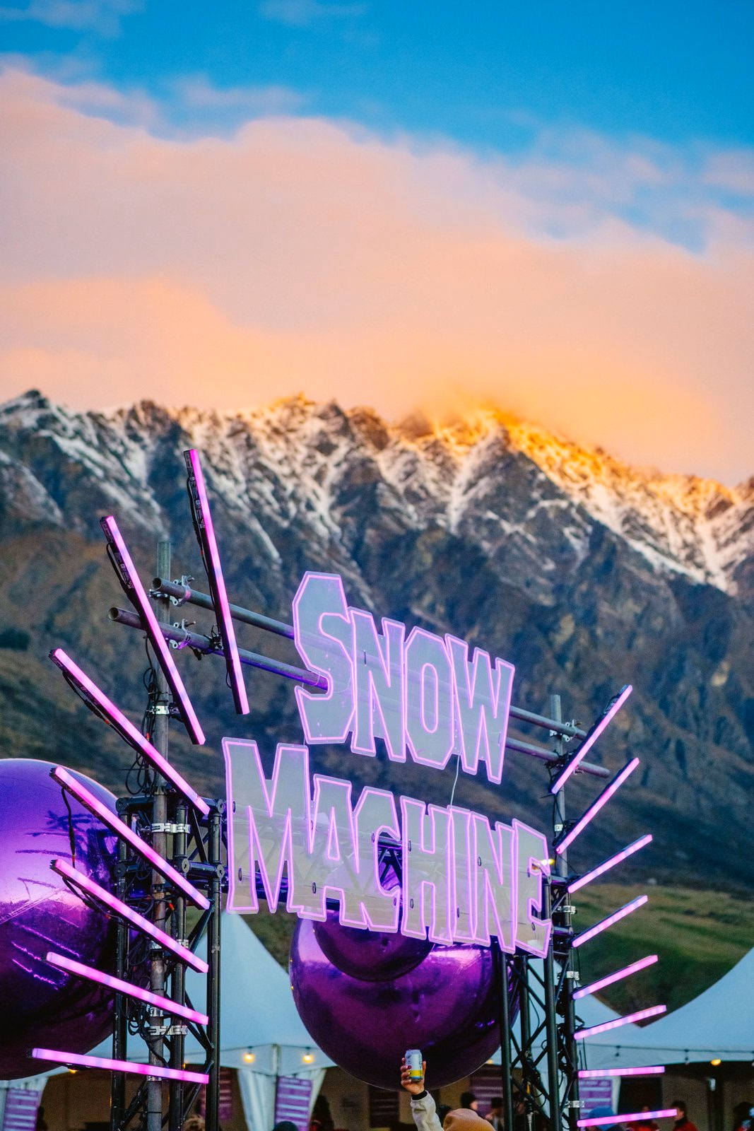 Snow Machine festival sign against snow-capped mountains