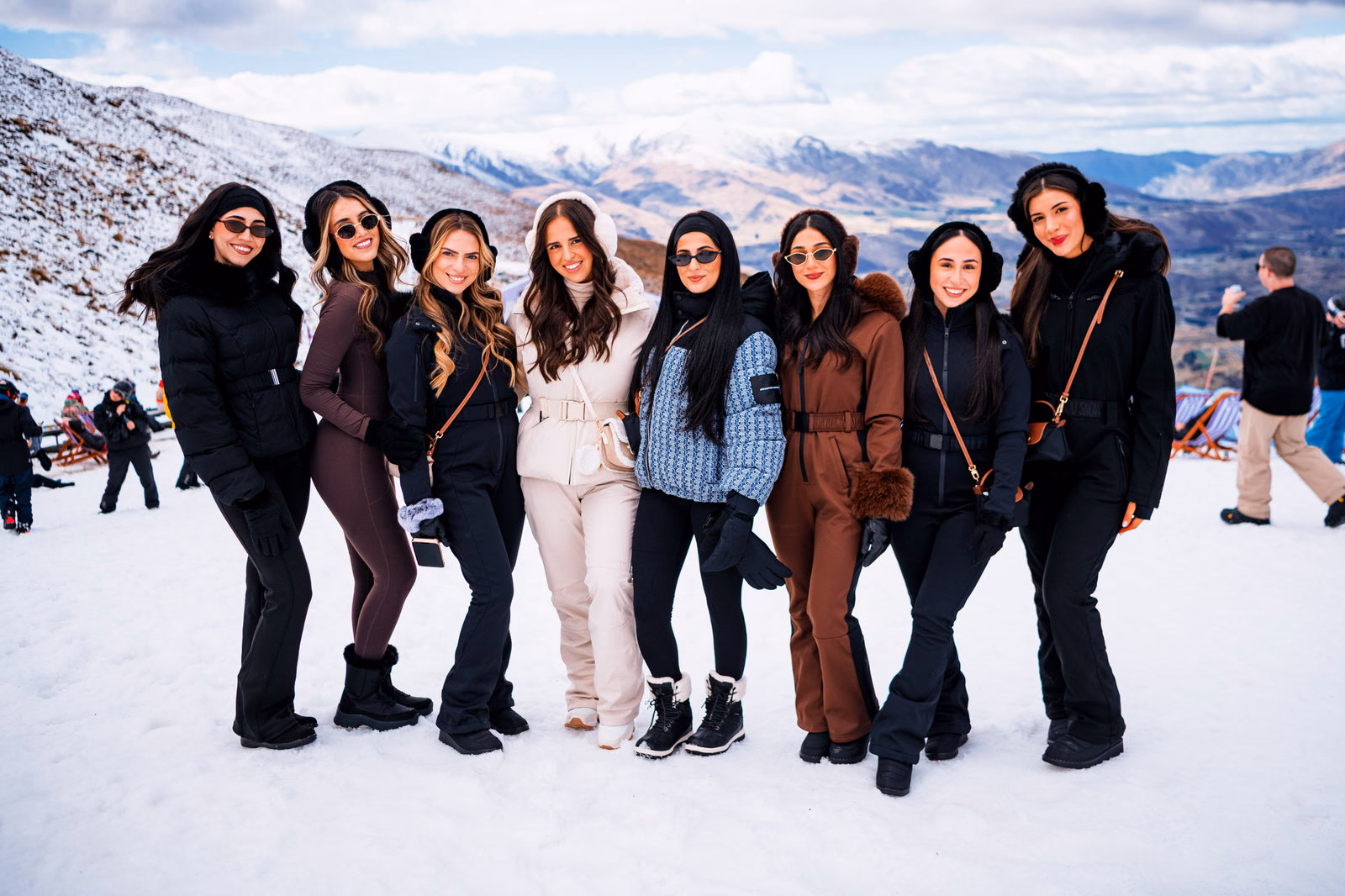 Group of eight friends posing on the snowy slope