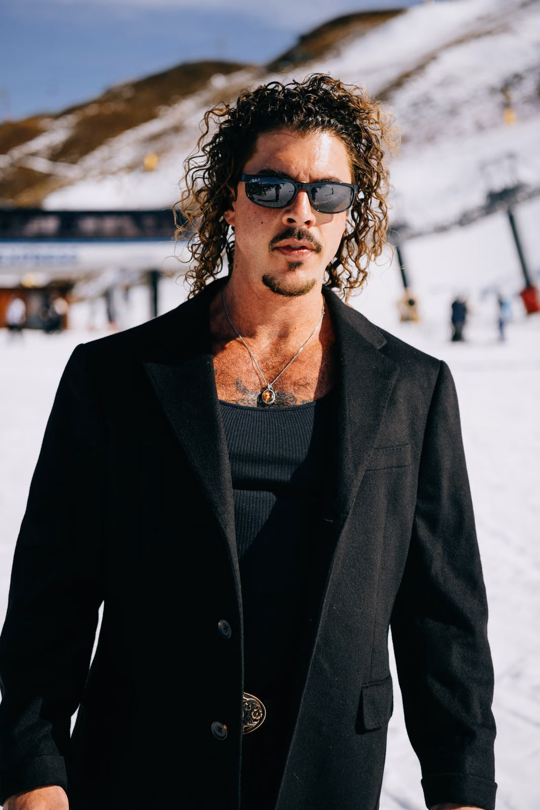 Keli Holiday in a black blazer and tank top standing in the snow at Coronet Peak