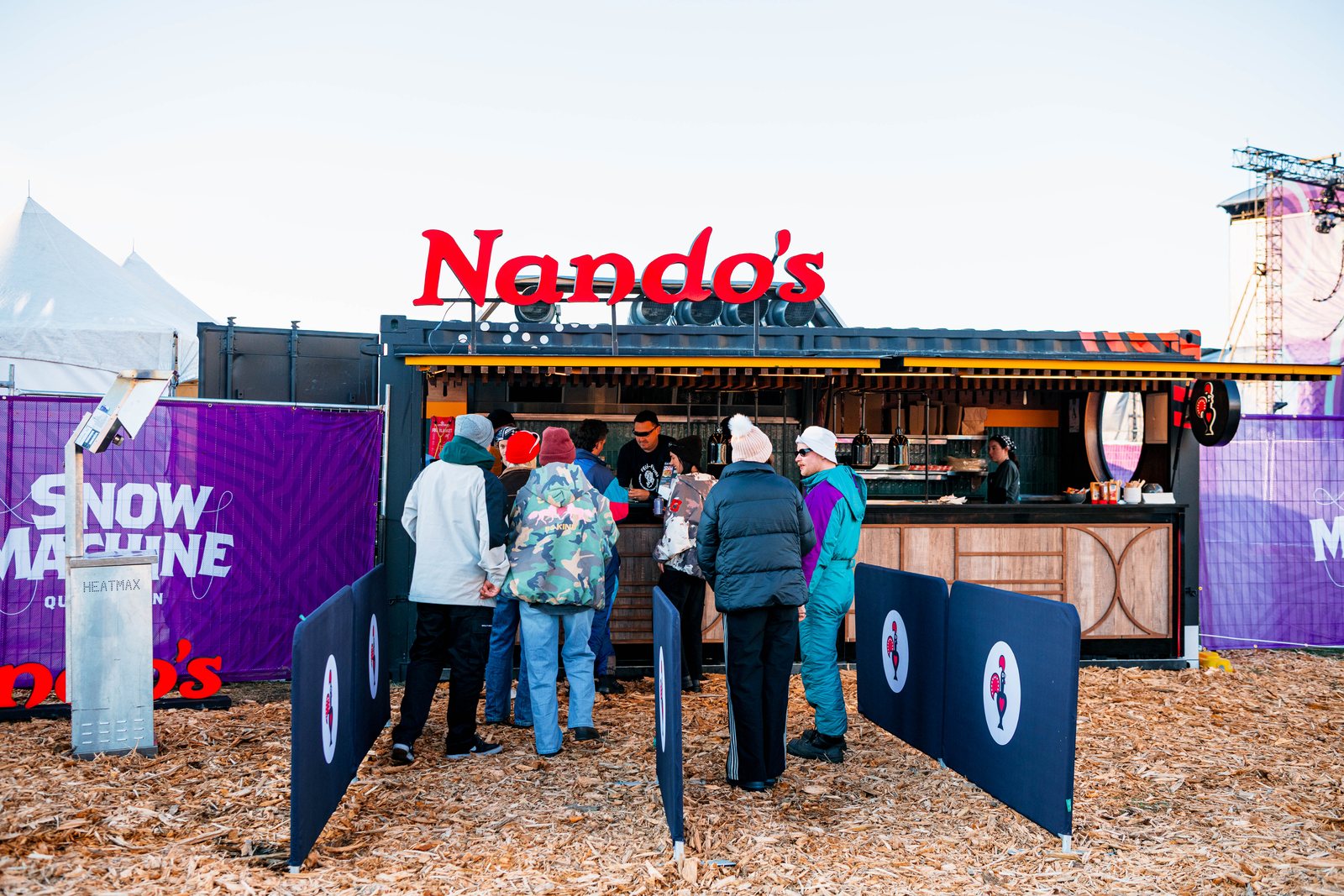 Festival-goers queuing at the red Nando's shipping-container stall in the daytime